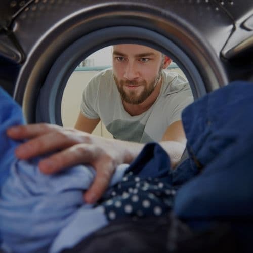 Self service laundry services photo showing a customer reaching into a laundry machine