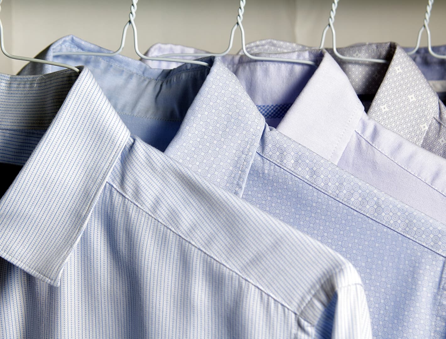 Image of a number of dress shirts hanging up on hangers